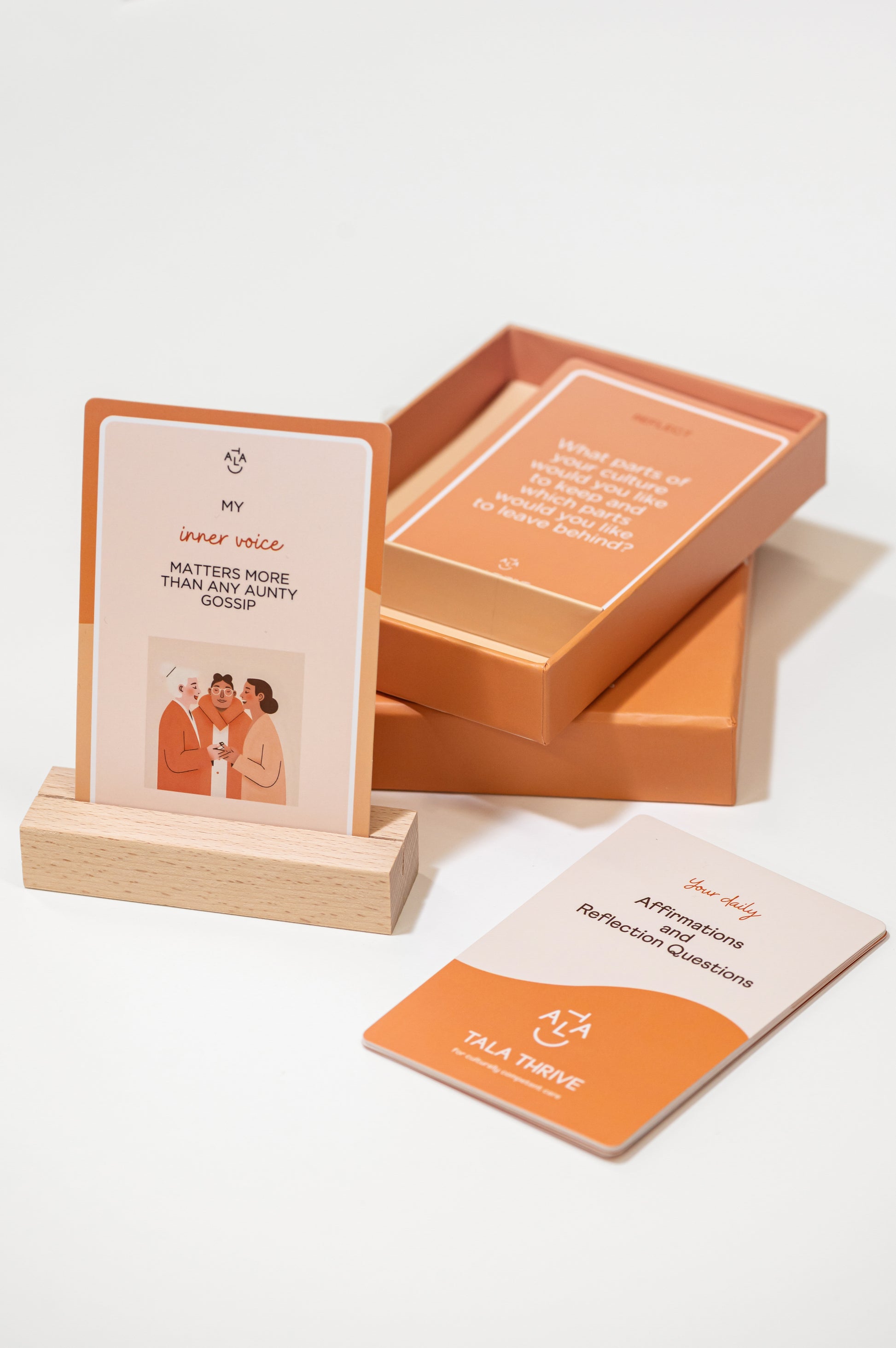 Tala Thrive Cultural Affirmation and Conversation Cards deck with wooden stand on neutral background. Aunty gossip